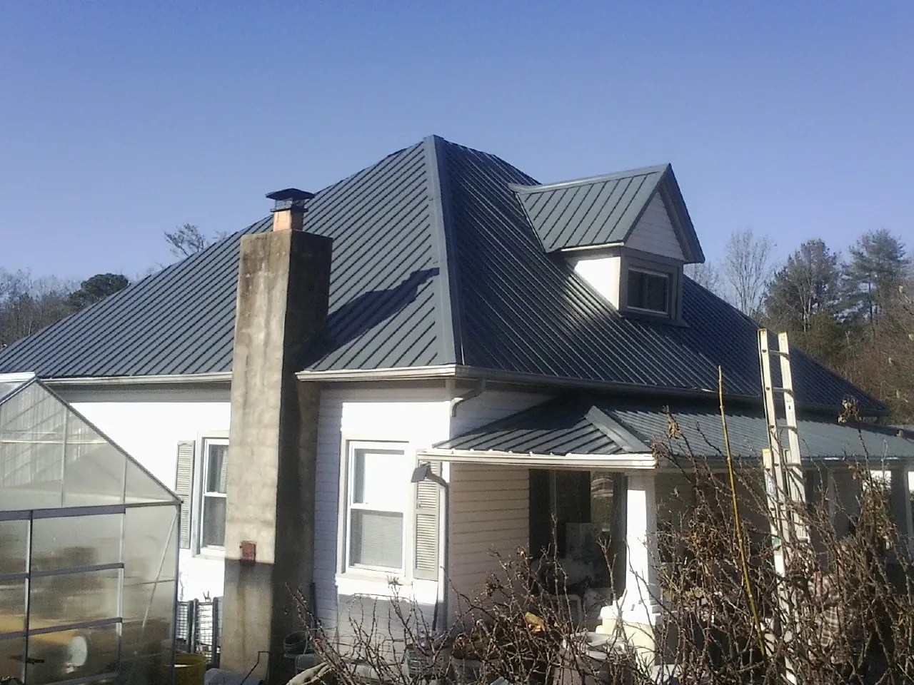 Dark blue standing seam metal roof on a white farmhouse with dormer — Slate & Tile Roof Repair by Roofing Brothers in Wilmette