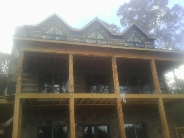 Dormers and porch framing on a large log home under construction — Roof Coating work by our crew in Wilmette
