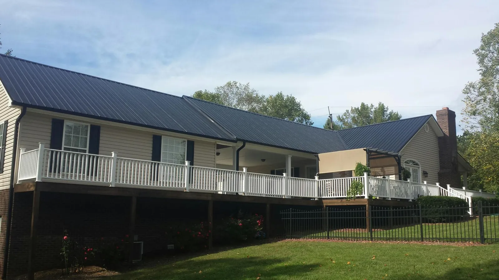 Black metal roof above a long white railed deck on a hillside home in Wilmette