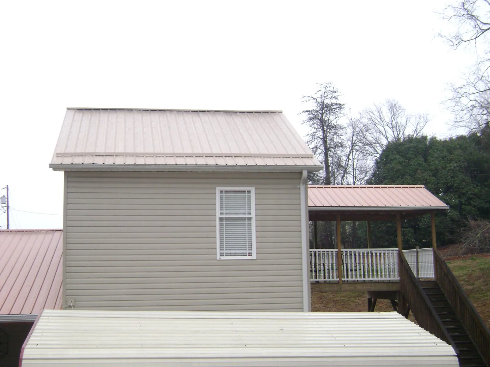 Tan metal roofs on a two story addition and attached porch, from a Roof Replacement job in Wilmette