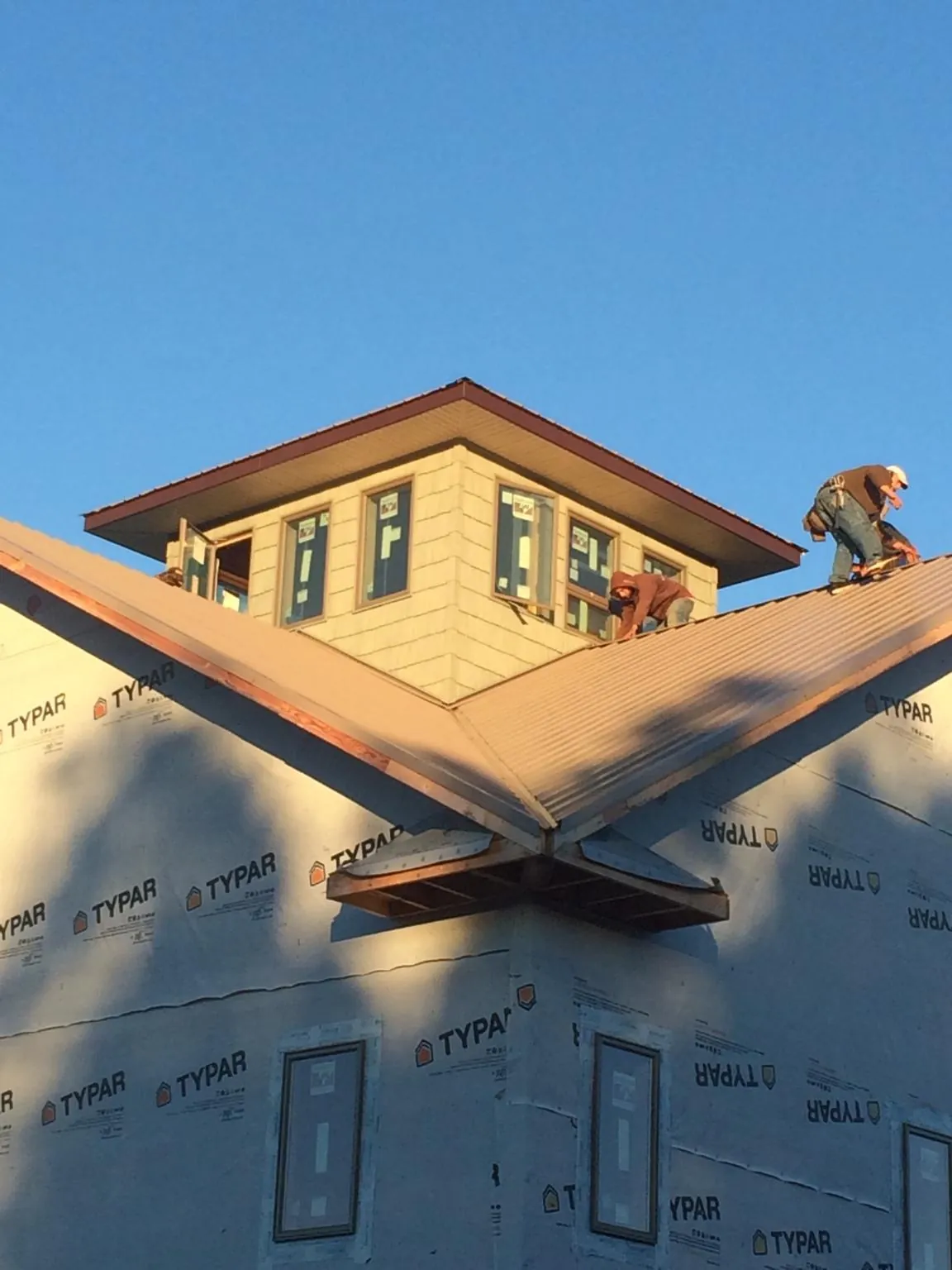 Roofers working around a rooftop cupola on a new metal roof at sunset — Roof Waterproofing in Wilmette by Roofing Brothers